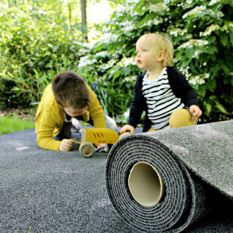 2 kids plying with a toy tractor on a garage carpet roll