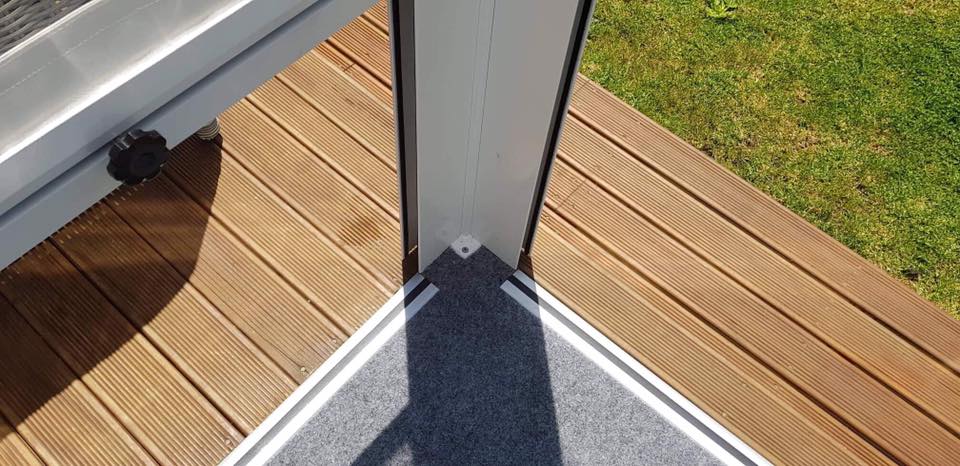 Outdoor patio with light grey carpet laid with aluminium edging surrounding it